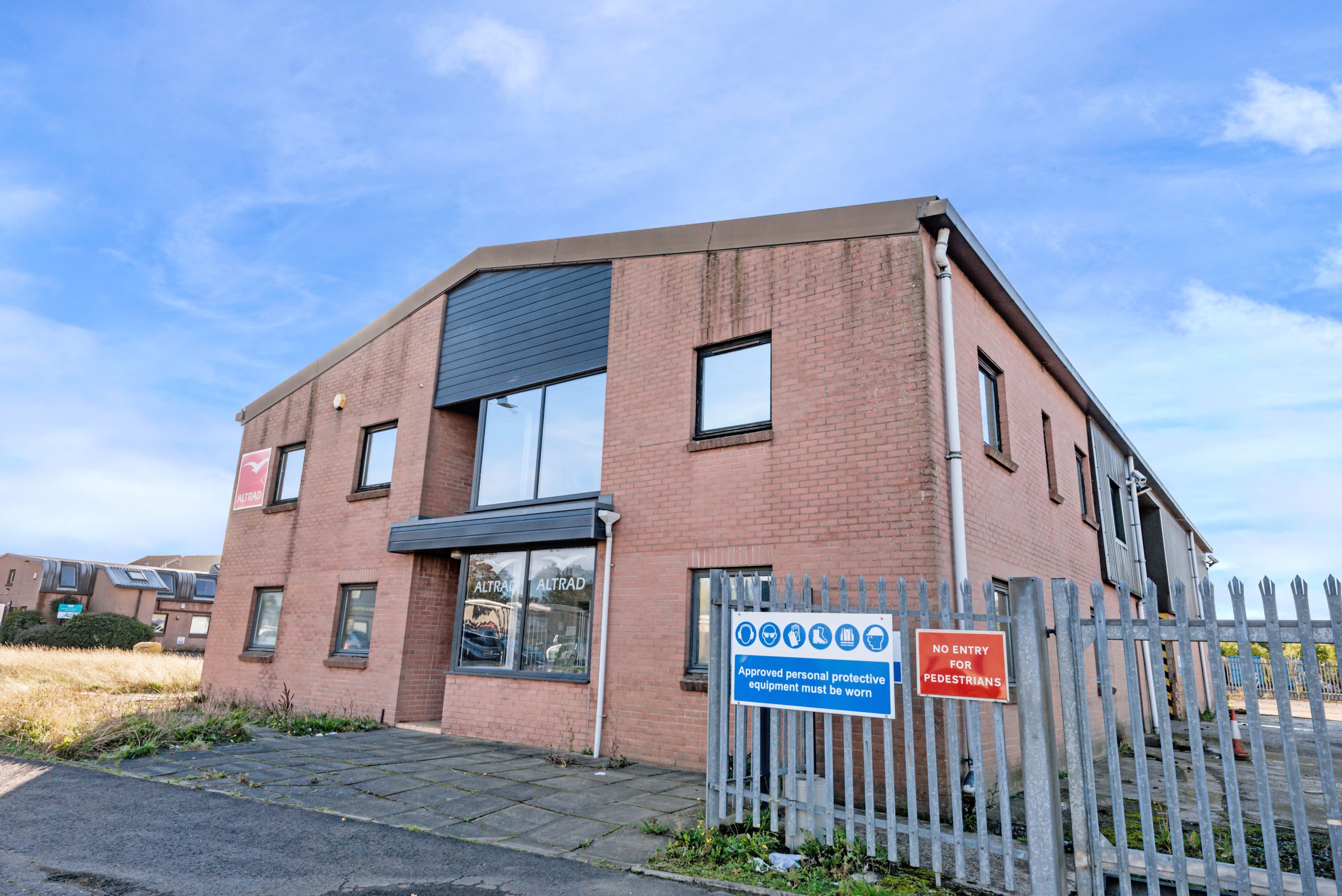 Two-storey brick industrial and office building at Mill Road Industrial Estate in Linlithgow, featuring large front windows, gated access, and private forecourt.