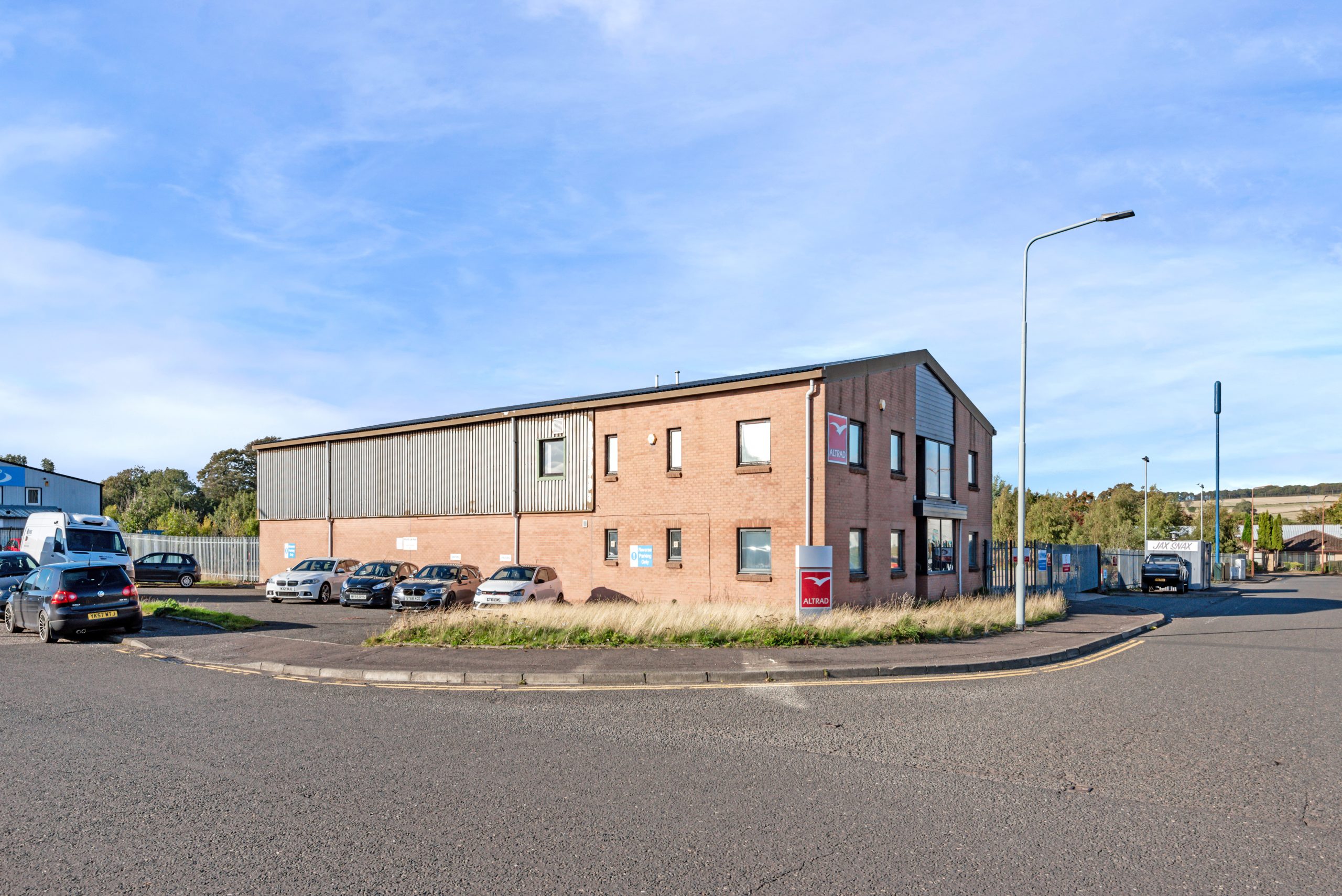 Two-storey industrial and office building at Mill Road Industrial Estate in Linlithgow with forecourt parking and countryside backdrop.