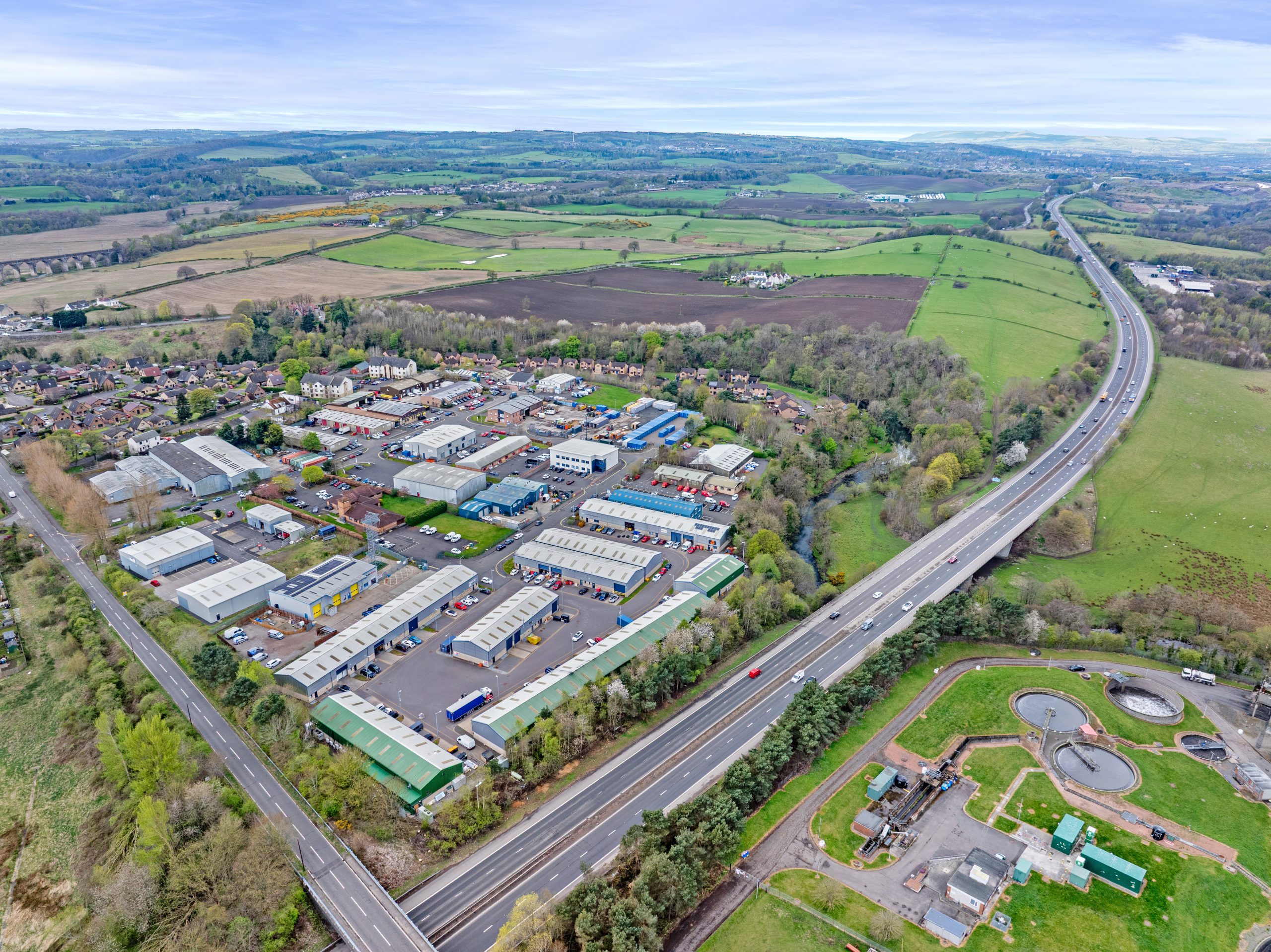 Aerial view of Mill Road Industrial Estate in Linlithgow, showing commercial buildings, warehouses, and surrounding infrastructure.