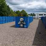 A central storage container at BOXXS Linlithgow featuring a large Rebel Bear mural, surrounded by other blue containers in an open industrial yard