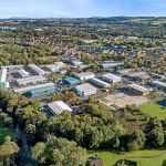 Aerial view of an industrial estate Linlithgow showing Mill Road Industrial Estate with surrounding businesses, road access, and green landscape.